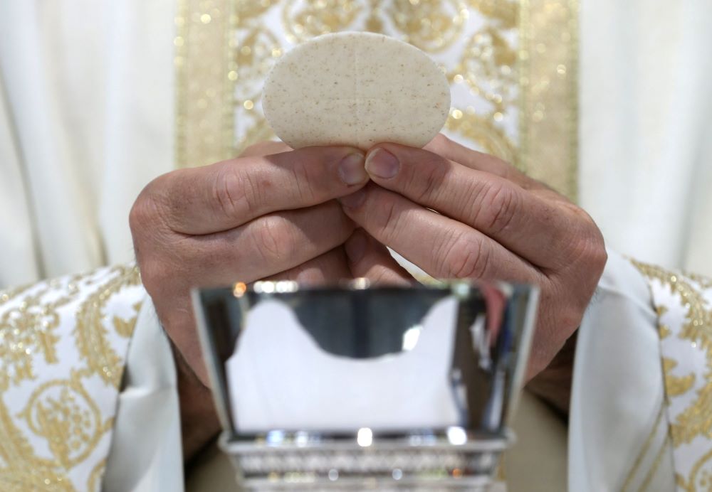 A priest holds the Eucharist.