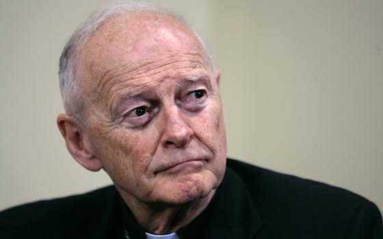 An older white man wearing a clerical collar stares off to the side with a serious expression